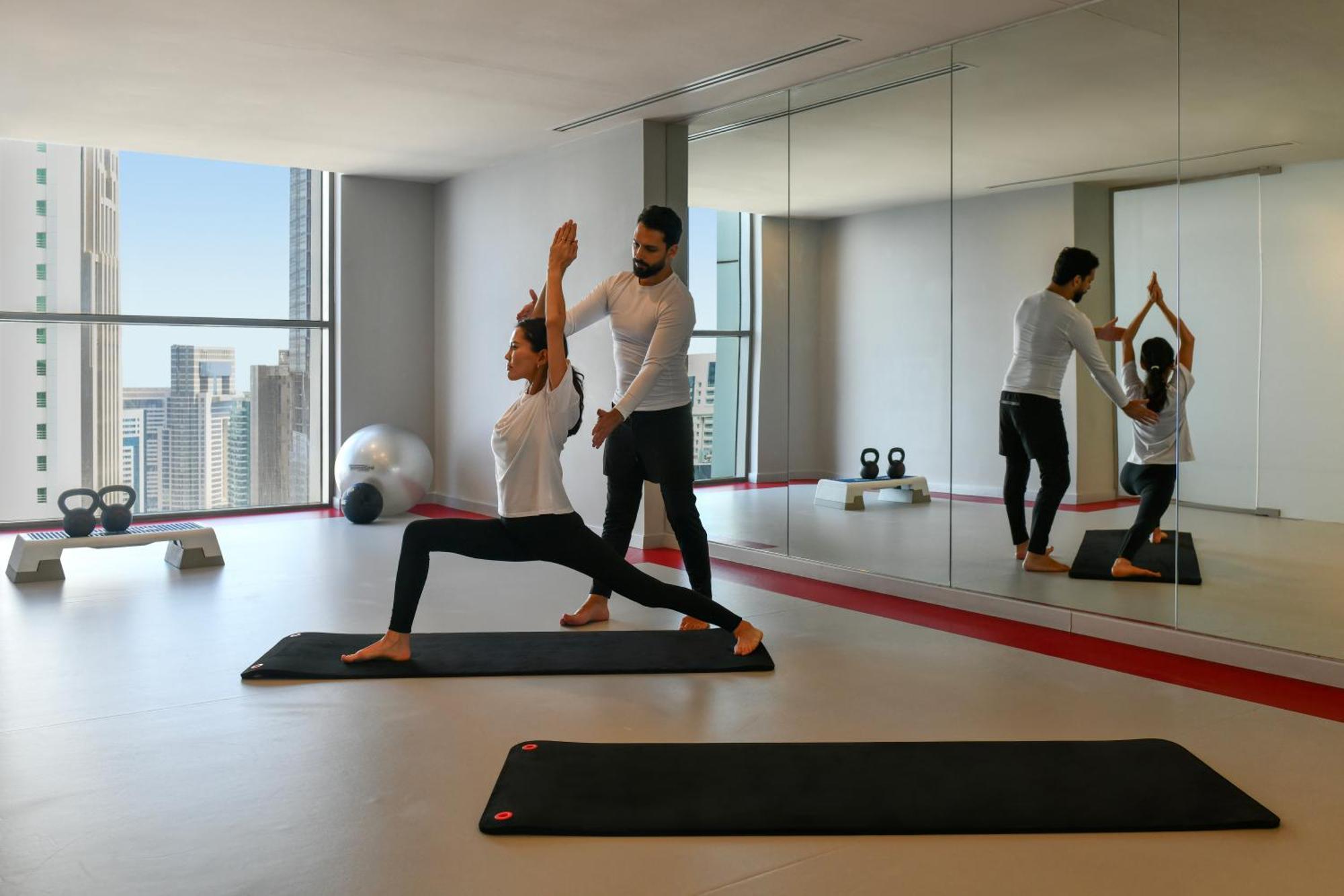 Dusit Doha Hotel Exterior foto A personal trainer assisting a woman with a yoga workout